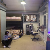 a man sitting in a room with bunk beds and a tv